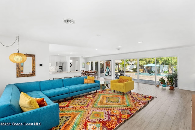 living room featuring light wood-style flooring, recessed lighting, and visible vents