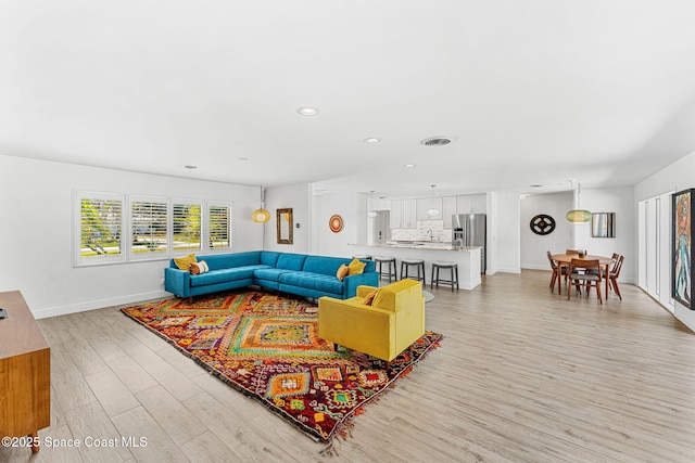 living area with light wood finished floors, visible vents, recessed lighting, and baseboards