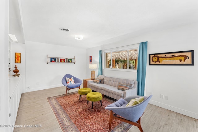 living area with light wood-style flooring, baseboards, and visible vents