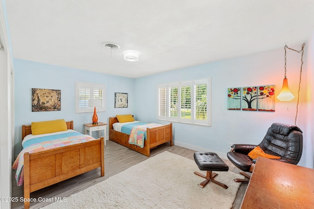 bedroom featuring wood finished floors, visible vents, and baseboards