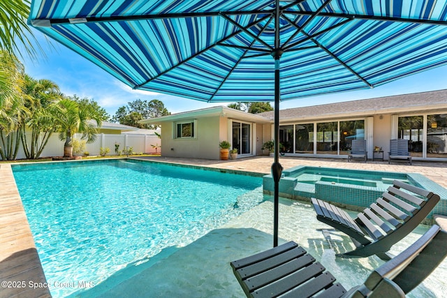 view of swimming pool featuring fence, a pool with connected hot tub, and a patio area