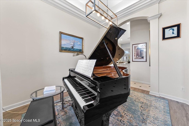 sitting room featuring arched walkways, ornamental molding, baseboards, and wood finished floors