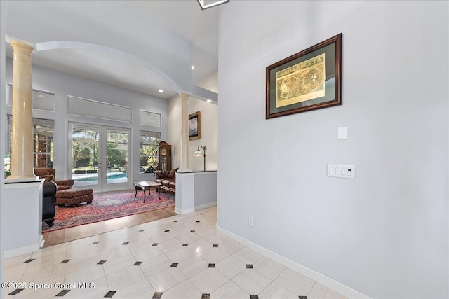 foyer featuring baseboards, recessed lighting, french doors, arched walkways, and ornate columns