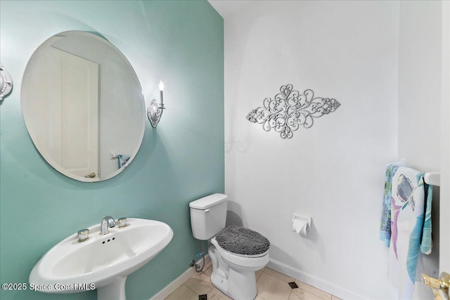 bathroom featuring tile patterned flooring, toilet, baseboards, and a sink