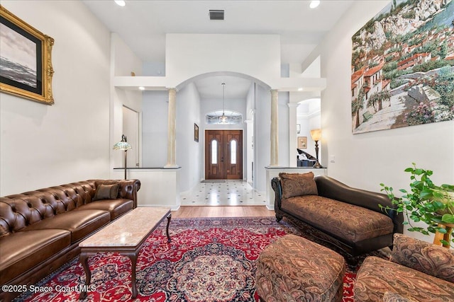 living area featuring visible vents, recessed lighting, wood finished floors, arched walkways, and ornate columns