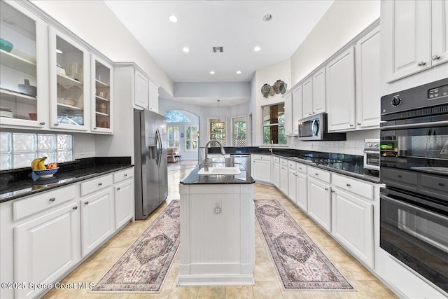 kitchen featuring a center island with sink, recessed lighting, arched walkways, stainless steel appliances, and white cabinetry