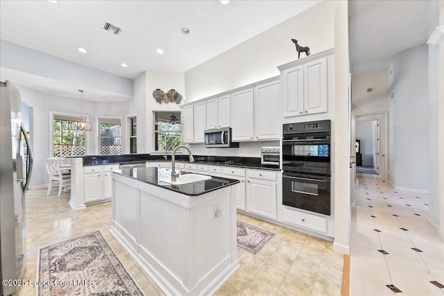 kitchen featuring dark countertops, visible vents, a healthy amount of sunlight, a peninsula, and black appliances