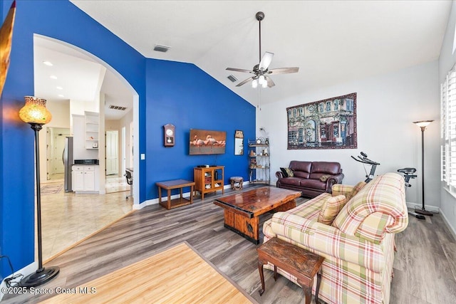 living room with visible vents, lofted ceiling, wood finished floors, arched walkways, and a ceiling fan