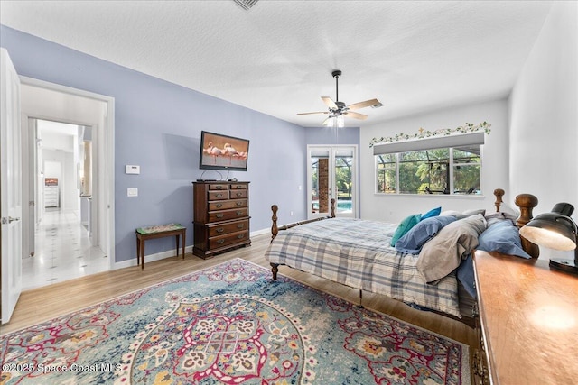 bedroom with baseboards, a textured ceiling, wood finished floors, and access to outside