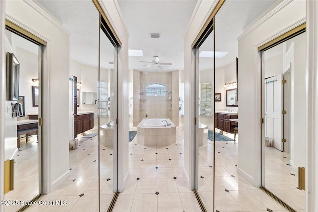 bathroom with a garden tub, two vanities, visible vents, and ceiling fan