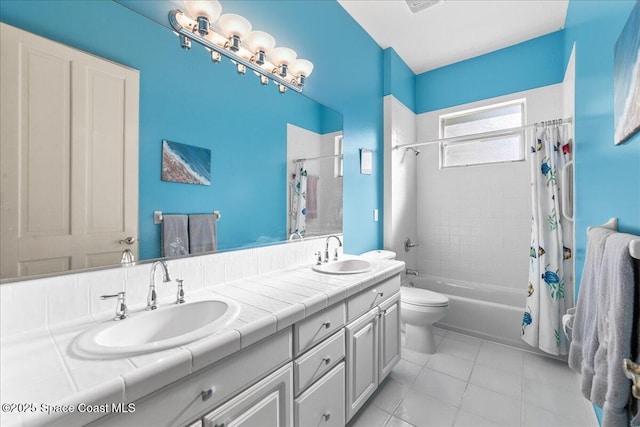 full bath with tile patterned floors, toilet, shower / bath combo with shower curtain, and a sink