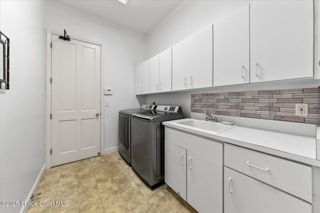 washroom with baseboards, cabinet space, independent washer and dryer, and a sink