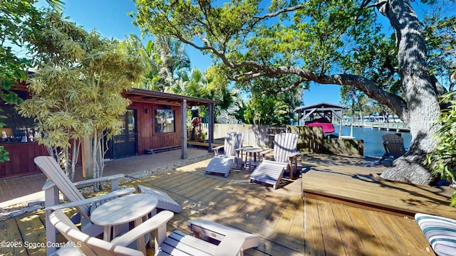 wooden terrace featuring fence, a water view, and a boat dock