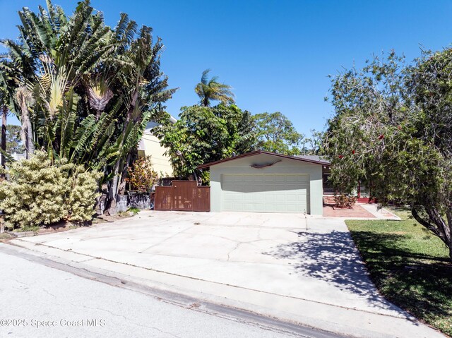 garage with concrete driveway and fence