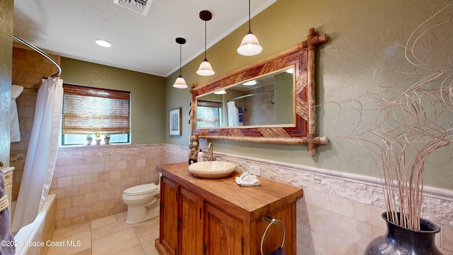 bathroom featuring a wainscoted wall, tile walls, toilet, and visible vents