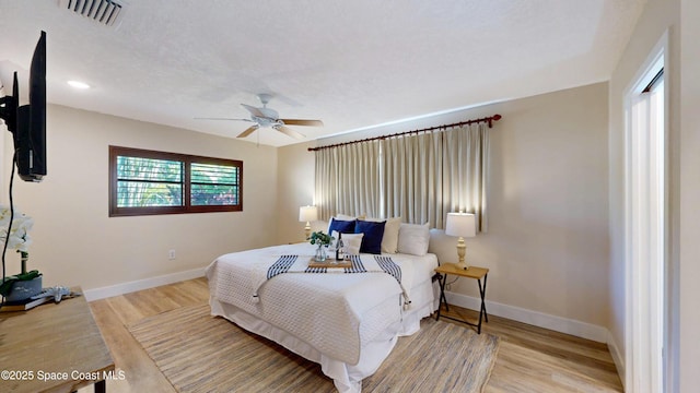 bedroom with visible vents, a ceiling fan, baseboards, and wood finished floors