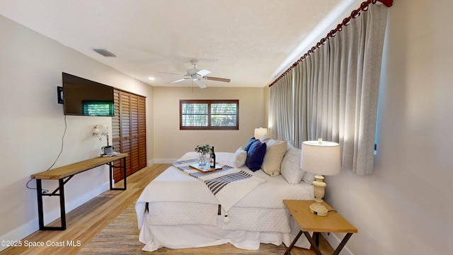 bedroom with visible vents, baseboards, light wood-style floors, and ceiling fan