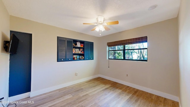 spare room with a ceiling fan, light wood-type flooring, and baseboards