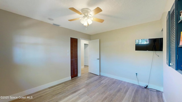 unfurnished bedroom with a ceiling fan, visible vents, baseboards, and light wood finished floors