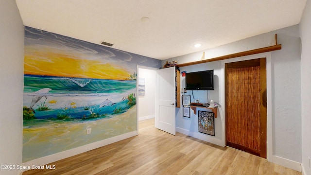 unfurnished room featuring visible vents, wood finished floors, and baseboards