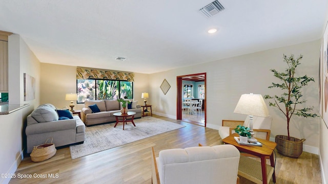 living area with recessed lighting, visible vents, baseboards, and light wood finished floors