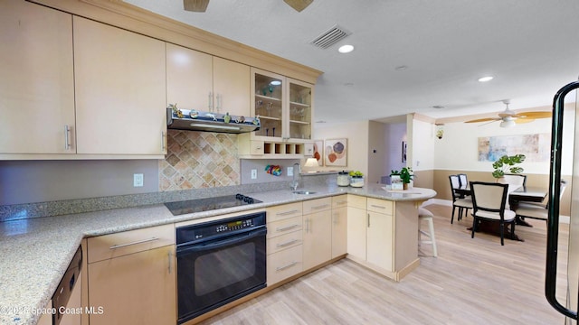 kitchen with visible vents, light countertops, light wood-type flooring, a peninsula, and black appliances