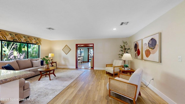 living area with visible vents, baseboards, and light wood-style flooring