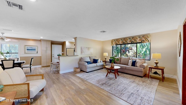 living room with light wood-style flooring, baseboards, and visible vents