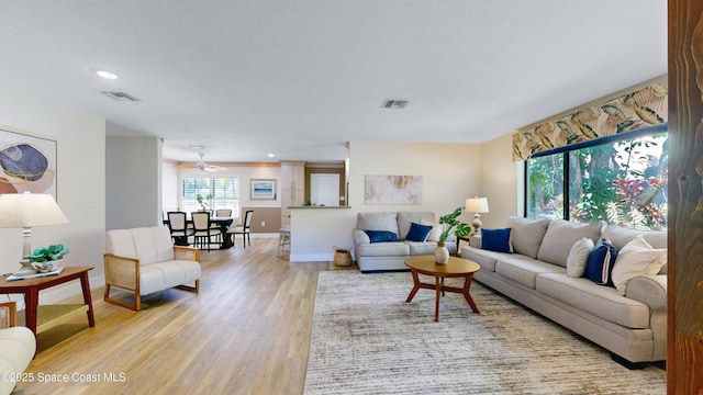 living room featuring light wood finished floors, visible vents, recessed lighting, and baseboards