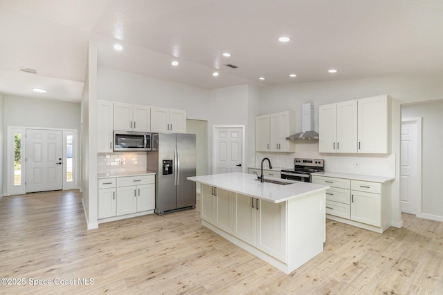 531 Ortega St SE, Palm Bay, FL 32909 - kitchen with a kitchen island with sink, a sink, stainless steel appliances, light wood-style floors, and wall chimney range hood