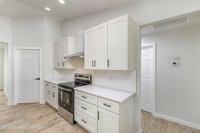531 Ortega St SE, Palm Bay, FL 32909 - kitchen featuring backsplash, wall chimney range hood, light countertops, light wood-style flooring, and electric stove