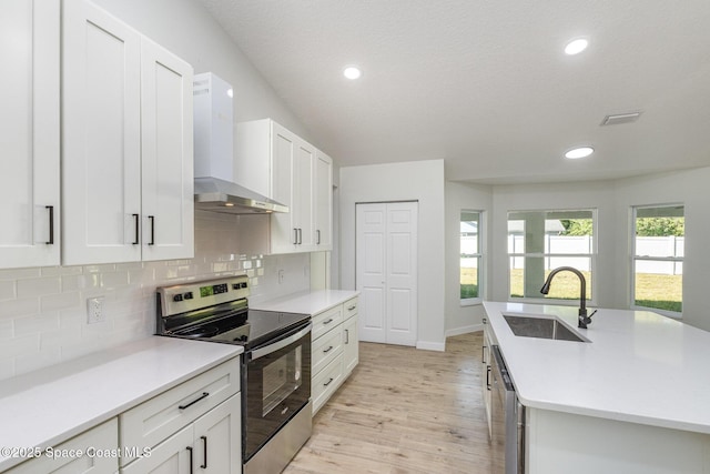 531 Ortega St SE, Palm Bay, FL 32909 - kitchen with light wood-style flooring, a sink, decorative backsplash, appliances with stainless steel finishes, and wall chimney exhaust hood