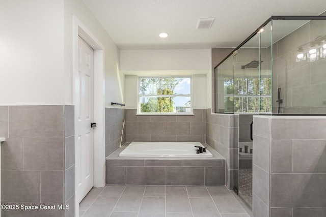 531 Ortega St SE, Palm Bay, FL 32909 - full bathroom with tile patterned flooring, visible vents, a shower stall, a bath, and tile walls