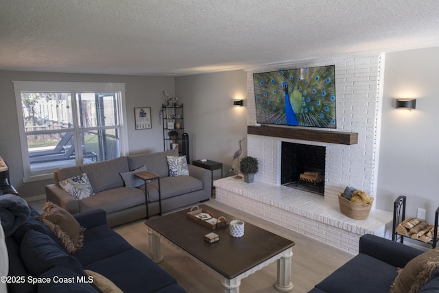 living room with a textured ceiling, a brick fireplace, and wood finished floors