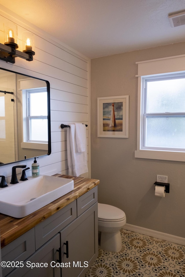 bathroom with vanity, toilet, visible vents, and a wealth of natural light