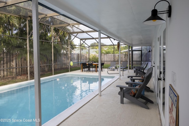 view of swimming pool featuring a patio area, glass enclosure, a fenced backyard, and a fenced in pool