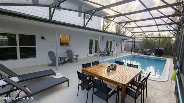 view of pool with glass enclosure, a patio, a fenced in pool, fence, and french doors