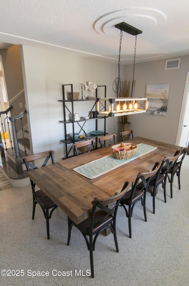 dining area with visible vents, a textured ceiling, speckled floor, and stairs