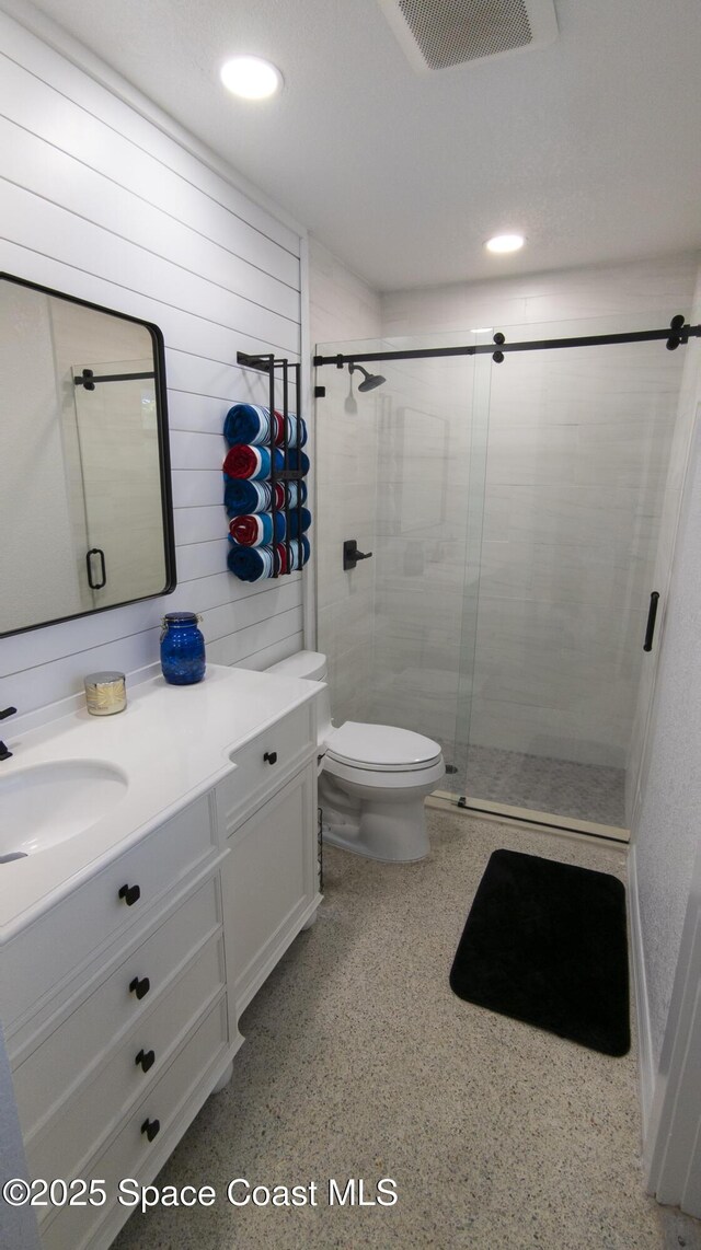 bathroom with vanity, speckled floor, visible vents, a stall shower, and toilet