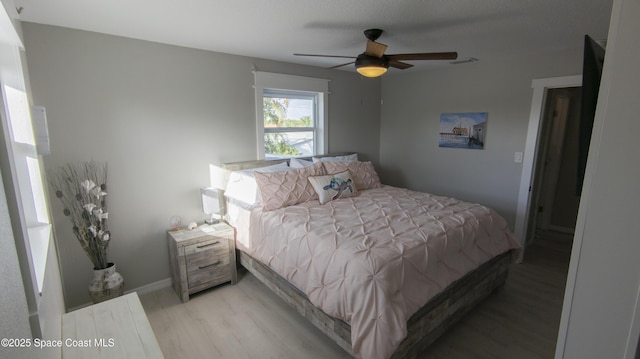 bedroom with visible vents, baseboards, light wood-style flooring, and a ceiling fan