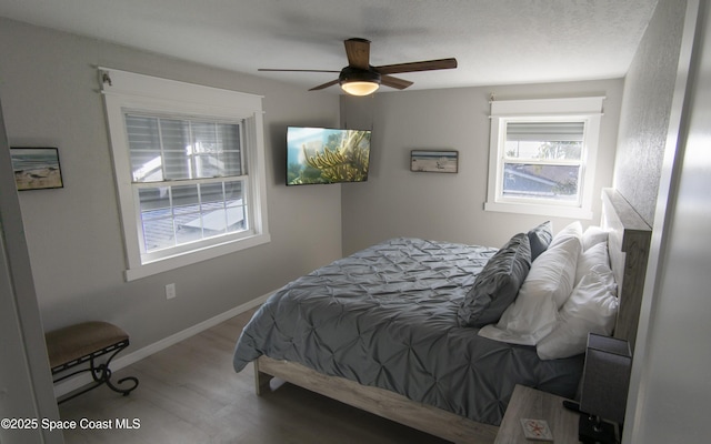 bedroom featuring baseboards, wood finished floors, and a ceiling fan