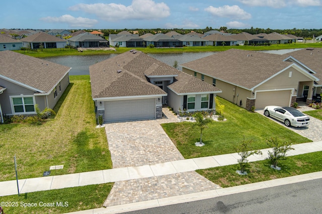 view of front of home with a residential view, a front lawn, decorative driveway, and a garage