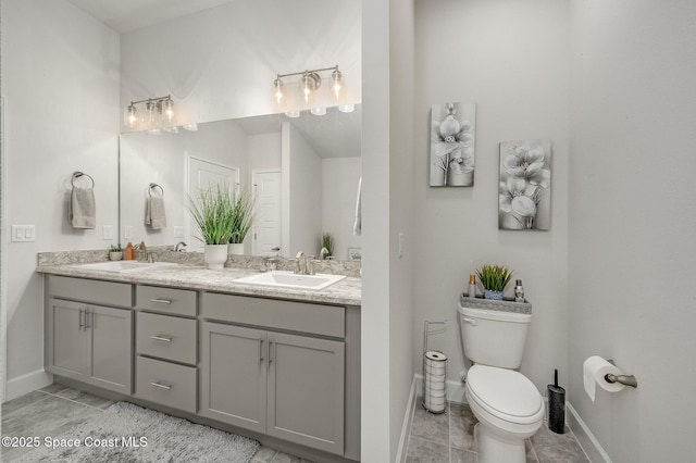 full bath featuring a sink, baseboards, toilet, and double vanity