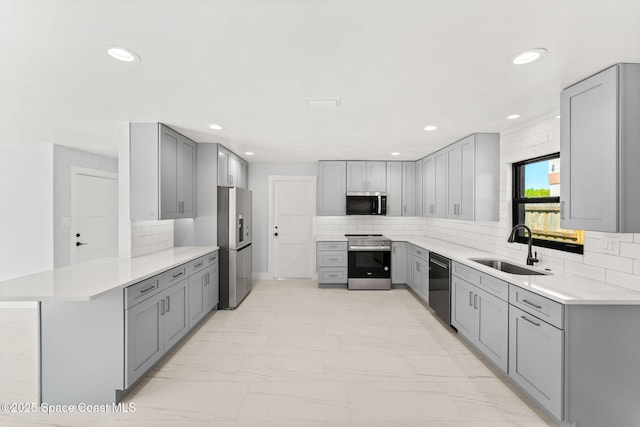 kitchen with a sink, gray cabinetry, marble finish floor, and stainless steel appliances