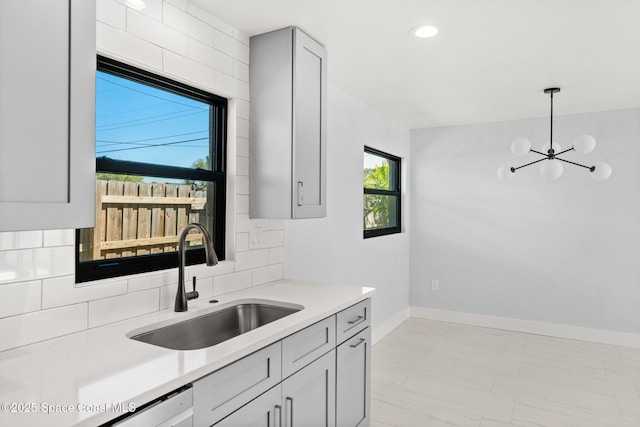 kitchen featuring a sink, baseboards, backsplash, and light countertops