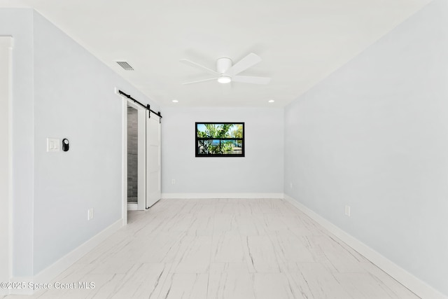 unfurnished room with a barn door, a ceiling fan, visible vents, and baseboards