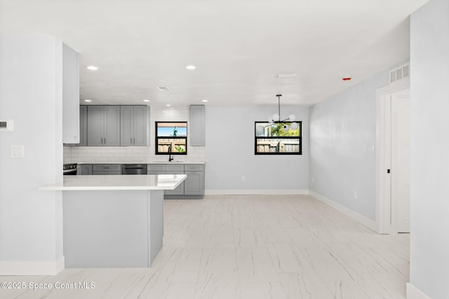 kitchen featuring dishwashing machine, gray cabinetry, visible vents, and a sink