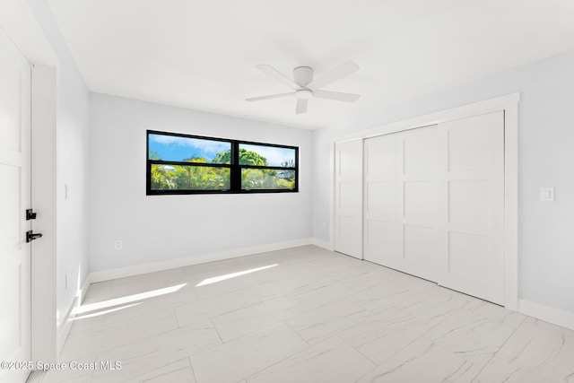 unfurnished bedroom featuring a closet, a ceiling fan, baseboards, and marble finish floor