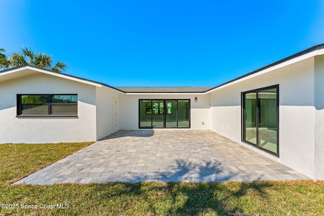 rear view of property with a patio area, stucco siding, and a lawn