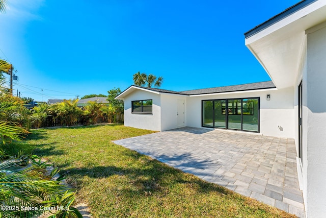 back of property with stucco siding, a lawn, and a patio area